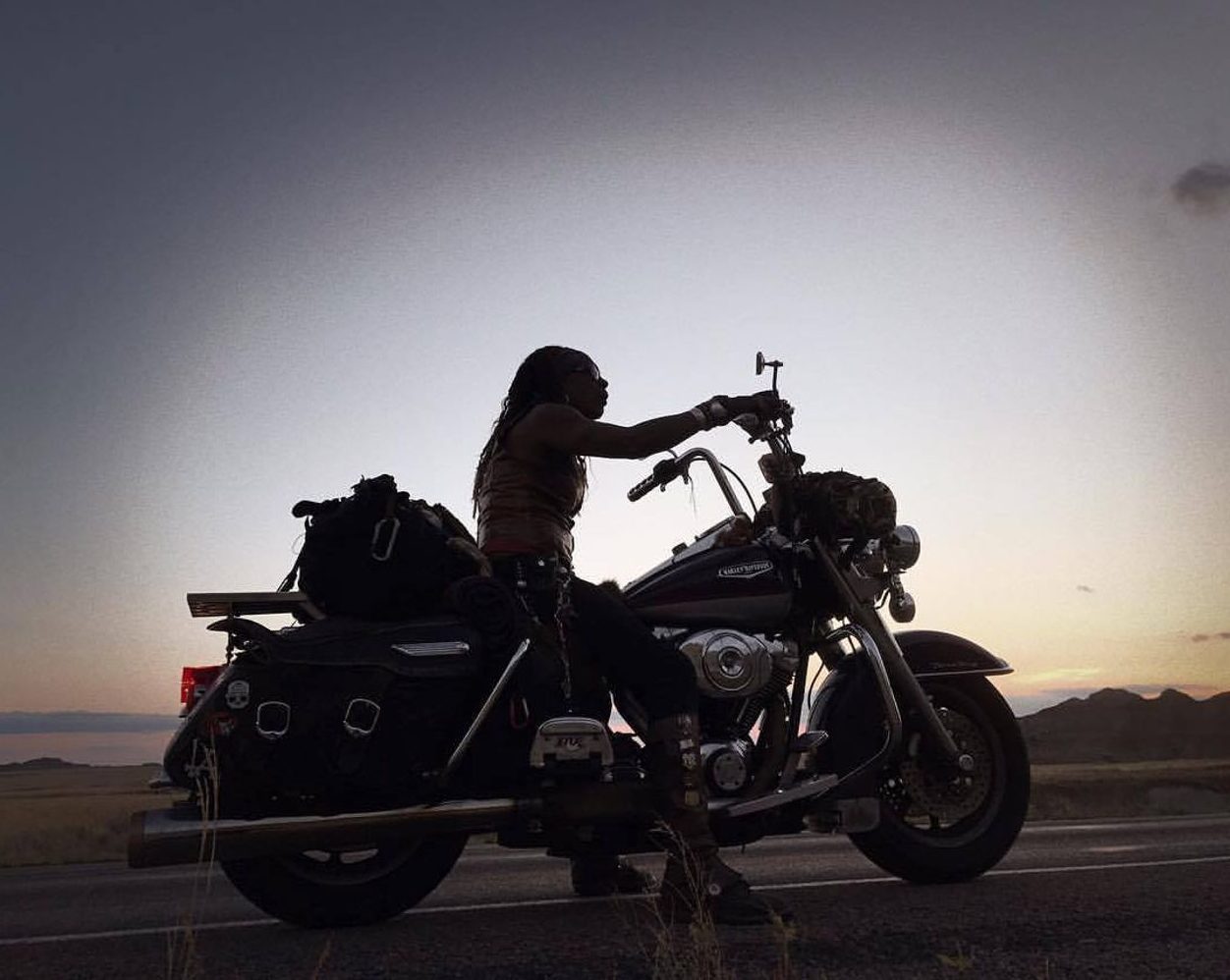 Gevin silhouetted on her motorcycle at dusk
