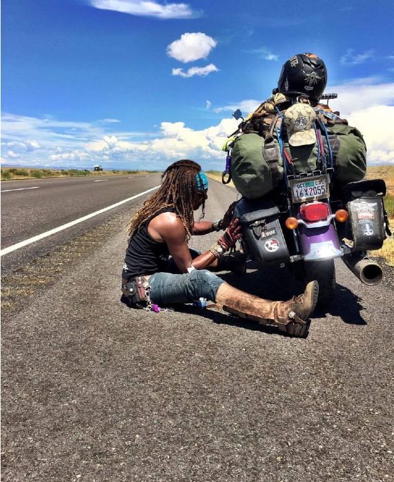 Gevin resting roadside beside her loaded touring bike