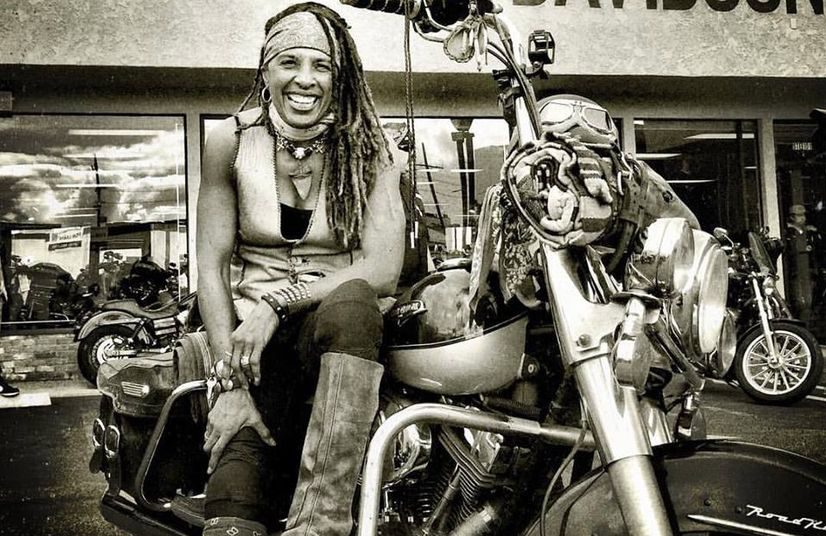 Black-and-white portrait of Gevin smiling beside her chopper