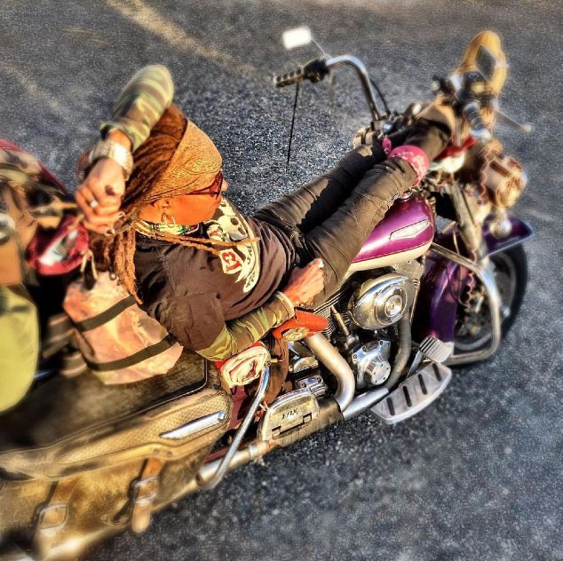 Gevin leaning over her motorcycle on the pavement